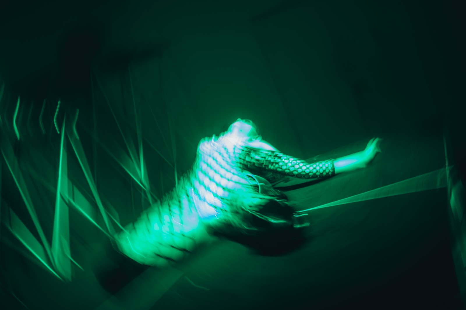 A performance artist bathed in green light