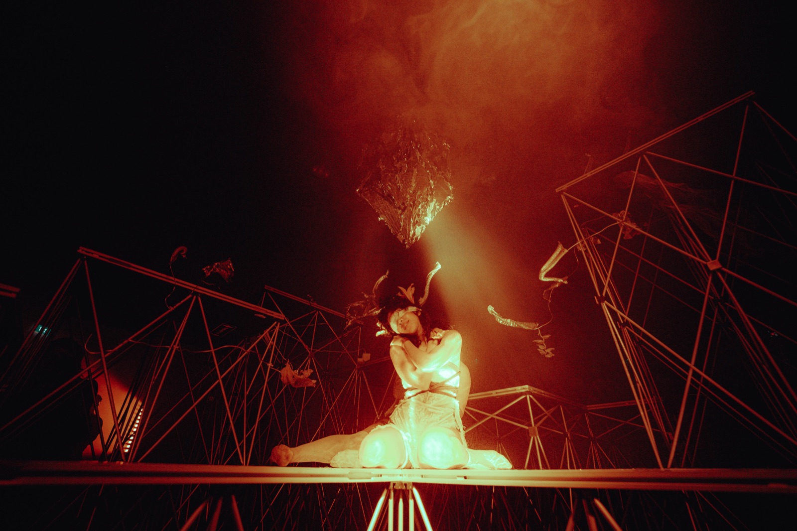 A performance artist on stage with another installation in view